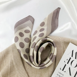 Detailed view of beige silk scarf with grey purple polka dots on a knit background