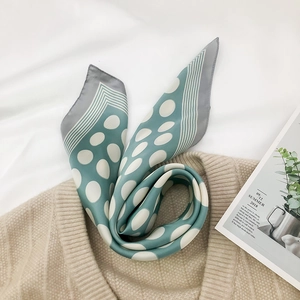 Light green silk scarf with large white polka dots and grey striped edges on beige fabric