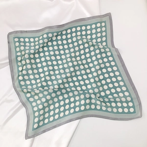 Detailed view of sage green silk scarf with white polka dots and striped borders
