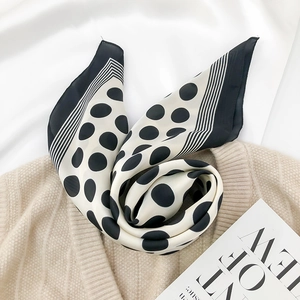 Detail of silk-like satin scarf with classic black and white polka dots and striped border