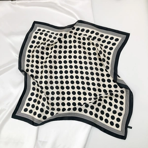 Detail of silk-like satin square scarf featuring classic black and white polka dot pattern