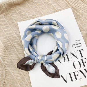 Detailed texture of blue silk-like square scarf with white polka dots and striped border