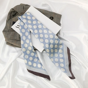 Detail of light blue polka dot silk scarf draped on a suit for a stylish fashion look