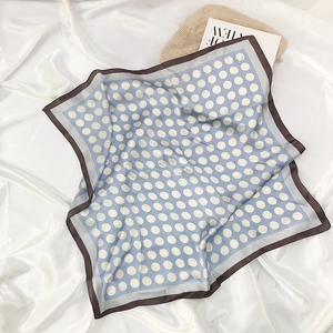 Detail of light blue polka dot silk scarf with brown borders on a white silk background