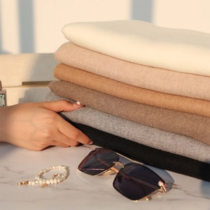 Detail of neatly folded cashmere-style scarves in elegant earth tones and soft textures