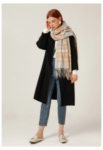 Close-up of a blue and orange plaid cashmere-like scarf with fringe on a model in winter coat