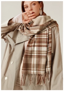 Close-up of classic earthy-toned plaid scarf with long fringe details and soft texture