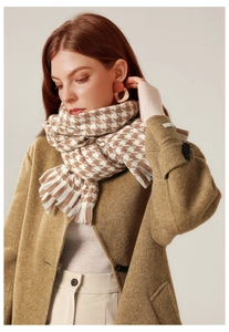 Close-up of a brown houndstooth tassel scarf styled with a camel wool coat and knitwear