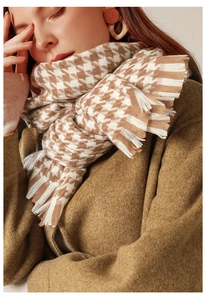 Detailed texture of beige houndstooth scarf with soft fringe edges and thick knit
