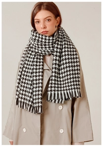 Detailed view of black and white houndstooth scarf with elegant fringe trim on a model