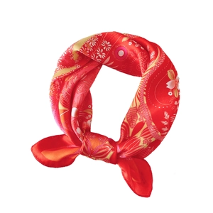 Carré de soie rouge à motif floral et ethnique noué en cercle sur un fond blanc pur