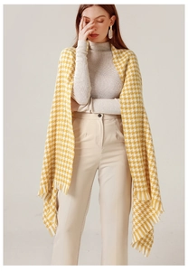 Detail of yellow and white houndstooth scarf with fringe tassels on a soft knit fabric