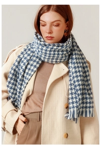 Detail view of blue and white houndstooth scarf with classic fringed edge on a model