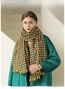 Detailed view of thick houndstooth plaid scarf with fringe paired with a dark green coat