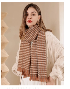 Detail of brown houndstooth scarf with fringe tassels worn over a cream knit sweater