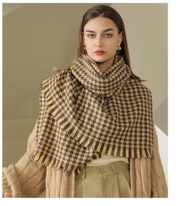 Detail of yellow and brown plaid scarf with tassels styled on a beige cardigan