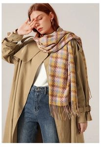 Détail d'une écharpe à motif pied-de-poule multicolore avec franges sur un trench-coat kaki