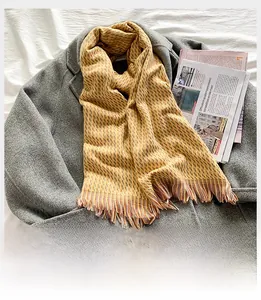 Détail d'une écharpe à carreaux jaune et orange avec franges sur manteau gris