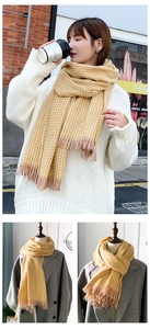 Détails d'une écharpe à carreaux jaune chaud avec franges sur pulls et manteaux