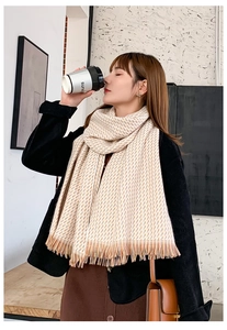 Détail de l'écharpe beige aux motifs géométriques orange et bords à franges