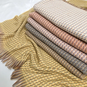 Détail d'écharpes à carreaux épaisses avec texture ondulée et pompons doux en plusieurs couleurs