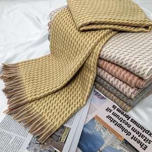 Détail d'écharpes d'hiver à carreaux avec franges courtes en jaune, beige et gris