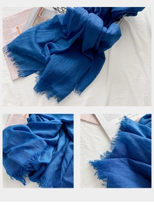 Détail de la texture de l'écharpe en coton bleu foncé et des bords à franges naturels