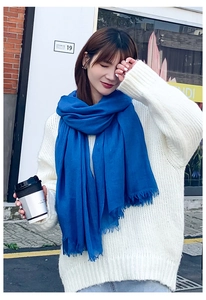 Détail d'une écharpe en coton lin bleu roi avec bords effilochés sur un pull blanc