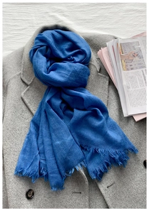 Détail à plat d'une écharpe bleu roi en lin et coton avec des bords effilochés naturels