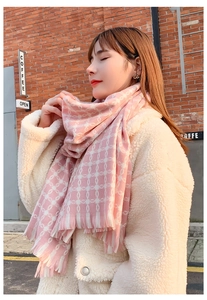 Close-up of pink plaid scarf with fringe details and soft white geometric patterns