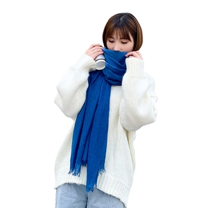 Écharpe bleu marine en lin avec franges portée comme châle chaud sur un pull blanc