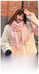 Pink and white geometric plaid winter scarf with fringe detail on a female model