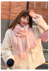 Outdoor close-up of pink cashmere-like scarf with white jacquard and fringe edges