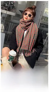Detail of red and green plaid scarf with soft tassels in imitation cashmere fabric