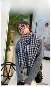 Close-up of black and white plaid scarf featuring classic fringe and soft knit texture