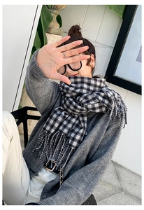 Detailed view of the thick black and white plaid scarf with long decorative tassels