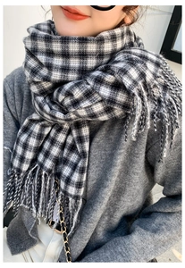 Close-up of black and white checkered scarf with soft tassel detail and thick knit texture
