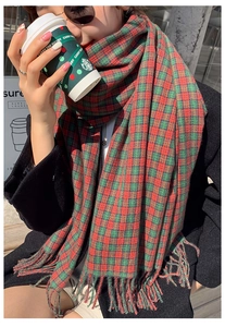 Detail of red and green plaid scarf with soft fringe edge on black wool coat