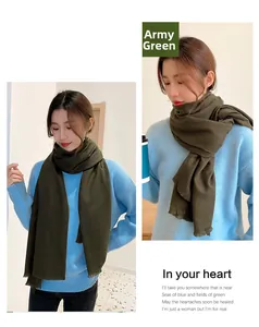 Detail view of army green cashmere-like scarf with fringe edges worn by a female model