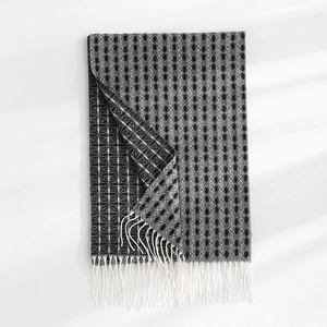 Detailed view of thick cashmere-like scarf with grey clover pattern and white tassels