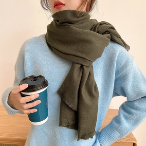 Olive green long cashmere-style winter scarf with tassels, worn with a cozy knit sweater