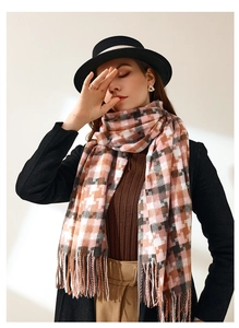 Détail d'une écharpe à carreaux rose et gris avec des pompons doux et élégants