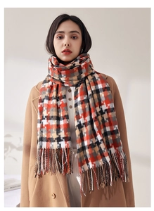 Détail de l'écharpe à carreaux doux avec longues franges en tons orange et gris chaleureux
