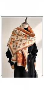 Close-up of beige floral cashmere-like scarf with fringe details on a black coat