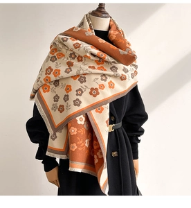 Detail of floral cashmere-like scarf showing warm orange texture and fringe edges