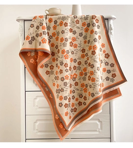 Detailed close-up of thick floral knit scarf texture and decorative fringe trim