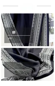 Detail view of navy blue silk scarf featuring white paisley patterns and fine stitching