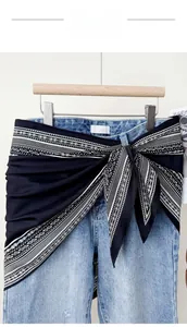 Detail of a silky black and white paisley print scarf used as a stylish waist accessory