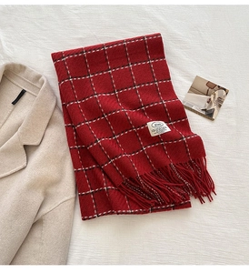 Close-up of red plaid cashmere scarf texture with tassels next to a wool coat