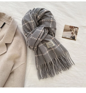 Close-up of grey plaid scarf texture with soft fringes and zian brand label detail